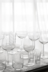 Several rows clear of glass for wine, champagne, water and other drink on grey concrete table at backlighting.