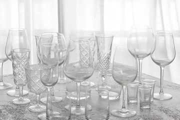 Several empty glasses for wine, champagne, water and other drink on grey concrete table at backlighting. Abstract tableware background with copy space