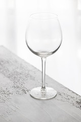 Close up of burgundy wine glass on concrete background at backlighting. Abstract drinking glass background