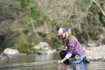 woman catching rainbow trout fly in river