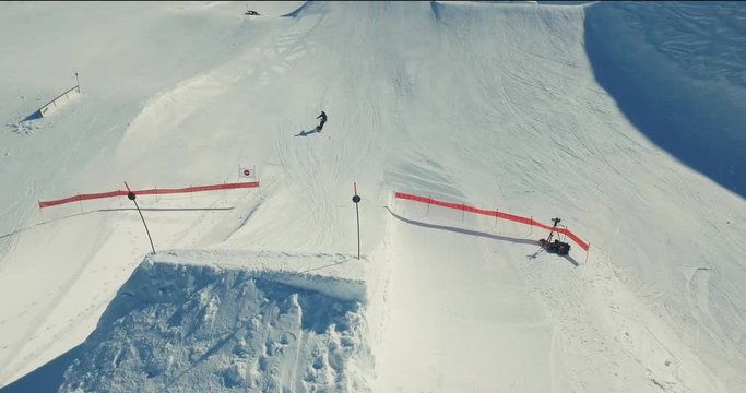 An aerial shot of a snowboarder going over a large kicker and doing a grab in the snowpark in Avoriaz, France