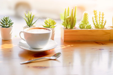 latte coffee in a classic white coffee cup decoration with cactus green leaf