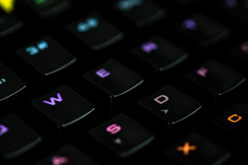 ..A gaming keyboard with rgb color backlight shot closeup on a black background with space for text. The concept of games, e-sports and the workspace of the gamer. Top view, macro. Desktop wallpaper.