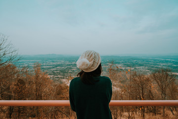 A woman looking over a landscape and yellow tree  at phu-thok thailand. orange and teal tone