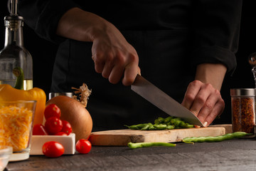 Cooking salad with vegetables, slicing fresh vegetables on a black background. Healthy and proper nutrition. Vegetation