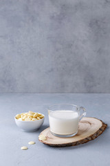 A cup of white hot chocolate on a wooden stand on a gray background. Keto drinks. Copy space.