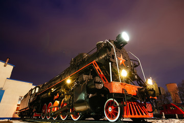 Old black steam locomotive on railway station at night