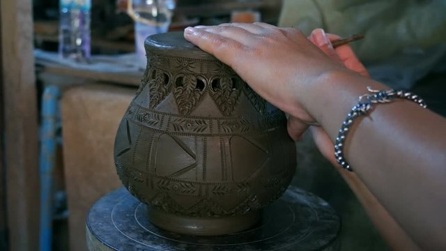 Hands make potter inflicts a decorative pattern on earthenware