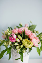 Bright bouquet with roses, eustoma and alstroemeria in white vase. Bouquet on soft blue background