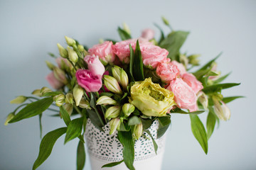 Bright bouquet with roses, eustoma and alstroemeria in white vase. Bouquet on soft blue background