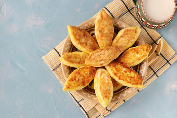 Cottage cheese pancakes, homemade traditional Ukrainian dish syrniki with semolina and cup of milk on a plate on a light blue background