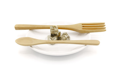 funny photograph of a small white plate, on a white background, with pieces of pyrite with a fork...