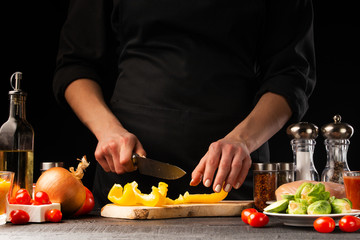 Cooking salad with vegetables, slicing fresh vegetables on a black background