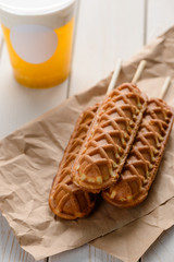 Three corn dogs and a cup of drink on rustic wooden table