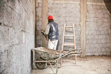 Real construction worker making a wall inside the new house.