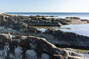 Rocky coast of Black Sea in village of Olginka, Tuapse district. Steep rocky slopes are composed of natural textures. Close-up. Fragments of rock of various sizes go into depths of sea.