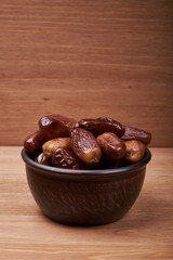 dried date fruit in bowl on wooden table background.