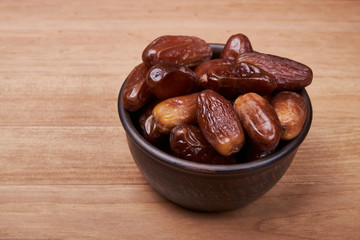 dried date fruit in bowl on wooden table background.