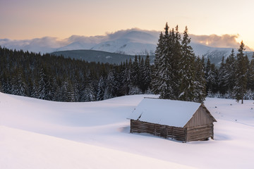 Charming snow-capped houses on a mountain Carpathian mountain valley, with magnificent views of peaks in winter.