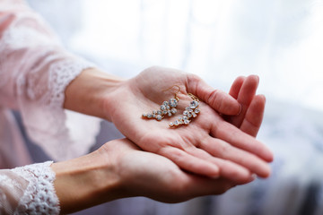 Obraz premium girl in a beautiful white dress holds earrings in her hands