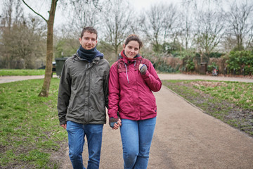 couple of friends walking through a park and looking at camera