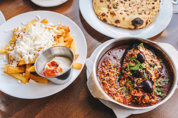 Balkan food - roasted eggplant in tomato sauce and cheese and french fries with cheese. Balkan restaurant.