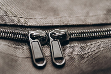 Two zipper clasps on the grayish suitcase