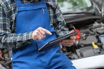 Mechanic using digital tablet for checking car engine