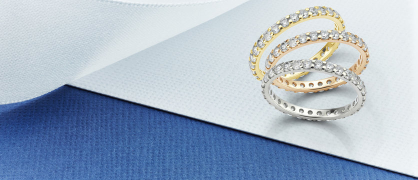 Eternity Rings on Blue and White Background. Featuring White Gold, Yellow Gold and Rose Gold diamond eternity ring banner on blue and white card. 