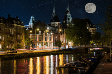 Fototapeta na wymiar Moon over Amsterdam at Night with a Canal and Reflections