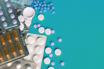 Assorted pharmaceutical medicine pills, tablets and capsules on blue background