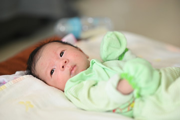 Close up image of Cute newborn baby lying on a comfortable bed with orderly bedroom as background.