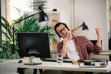 Attractive businessman in office. Young programmer with headphones singing at work.	