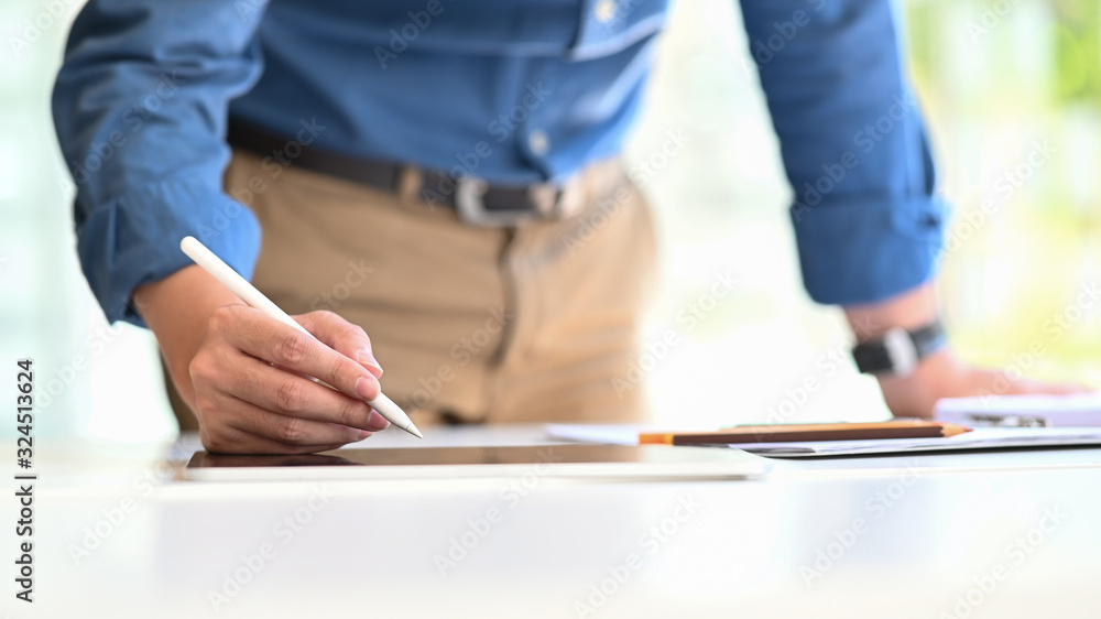 Poster creative man working as architect standing and writing/drawing at computer tablet that putting on mo
