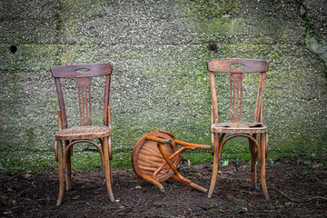 old wooden chairs with an abandoned concrete wall