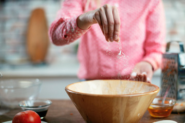 Close up of female hands putting salt in food. Woman cooking in kitchen. 
