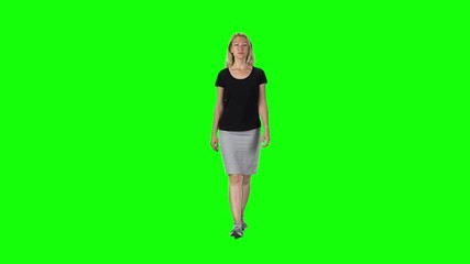Blonde girl in a black t-shirt, grey skirt and sneakers going against a green screen. Slow motion