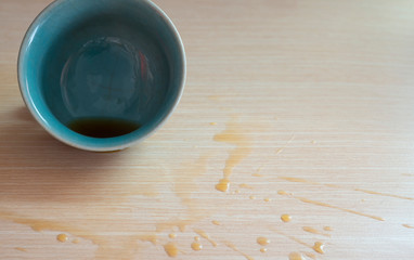 A cup of coffee and tea spilled on the wood floor