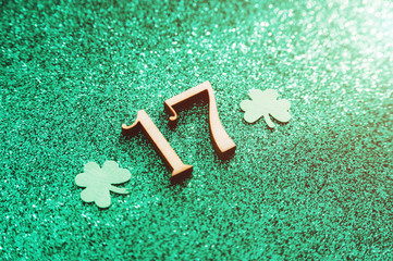 A paper leaf of clover and the number 17 on a shiny green background. Background for St. Patrick's...