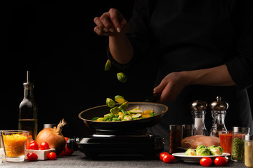 cook prepares for frying in a pan. Against the background of vegetables, falling brussels sprouts, freezing in motion