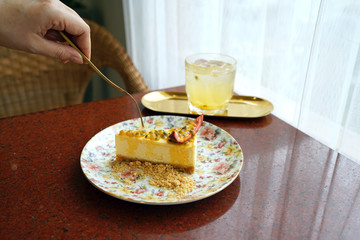 A plate of homemade cheesecake topped with fresh passion fruit sauce on wooden table and blurred background.