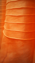 Close up on abstract textured orange fabric with sewing line details 