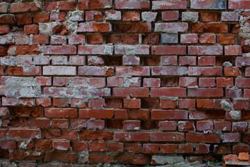 Old broken, damaged and corroded brick wall with broken bricks missing and leaving holes in the wall for background or wallpaper