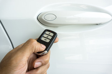  Hand holding car remote control on blurred car background. 