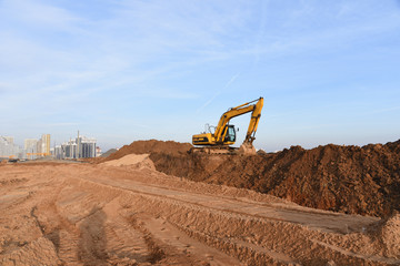 Yellow excavator during groundwork on construction site. Hydraulic backhoe on earthworks. Heavy...