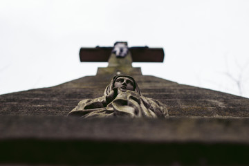 Close up outdoor view of stone cross with Jesus Christ and Virgin Mary. Faith symbol. Abstract melancholic image