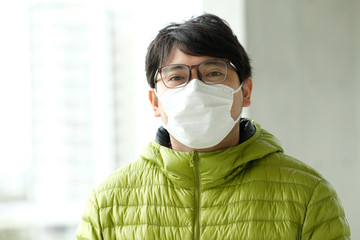 屋外で感染症予防の為に衛生マスクをしている眼鏡をかけた日本人男性のバストアップ正面
