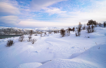 winterlandscape with dramatic sky on Kvaloeya Island near Tromsoe in northern Norway, landscape photography