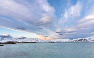 winterlandscape with dramatic sky on Kvaloeya Island near Tromsoe in northern Norway, landscape photography