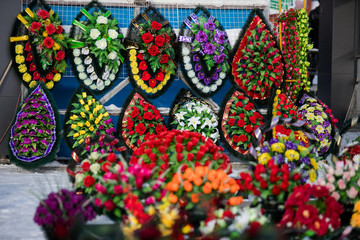 a point of sale with many artificial flowers, bouquets and wreaths near the cemetery sells jewelry and traditional offerings to the graves of the dead in memory of living relatives